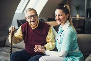 Nurse home caregiver is assisting old man at his home. Professional health support for elderly people. photo