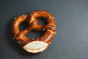 Traditional soft pretzel for Octoberfest on black background, copy space photo
