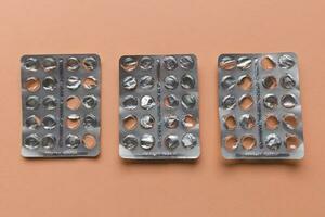 Empty pill blister on brown background, supplement concept photo