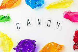 Colorful candy wrappers and text CANDY on white background photo