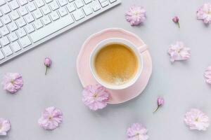 Still Life with computer keyboard and coffee on on spring pink background with flowers photo