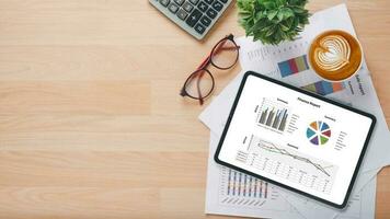 Tablet with charts and reports on office desk workplace. Top view flat lay photo