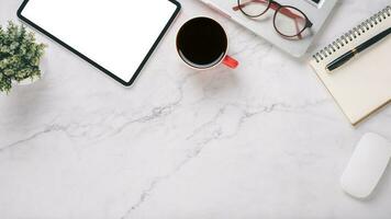 White office desk workplace with blank screen tablet, laptop, mouse, notebook, pen and cup of coffee, Top view flat lay with copy space. photo