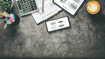 Tablet and smartphone with charts and reports on office desk workplace. Top view flat lay photo