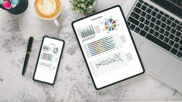 Tablet and smart phone with charts and reports on office desk workplace. Top view flat lay photo