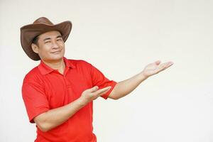 Handsome Asian man wears hat, red shirt, pose hands to present something, feels confident. Copy space of adding text or advertisement. photo