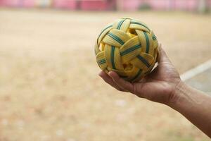 Closeup man hold Sepak Takraw ball outdoor. Concept, Asian traditional sport. A ball made of rattan or synthetic plastic. Sport with equipment that can play for outdoor or indoor. Competitive game. photo