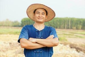 Handsome Asian man farmer wears hat, blue shirt,crossed arms on chest feel confident. Concept ,Agriculture occupation. Thai Farmer . photo