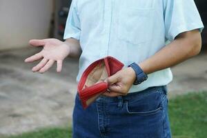 Closeup man holds empty red wallet with no momey. Concept, no money, poor, bad economic crisis. Financial problems. Broke or less money at the end of month. lost money. photo