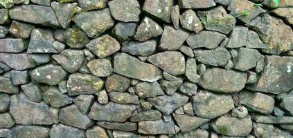 Stone walls, old stone textures, stone fences or piles of rocks arranged as a parapet on the outskirts of a green forest, Indonesia. photo