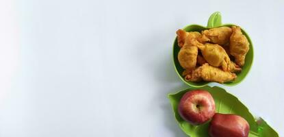 frito dulce plátano o pisang Moleng en plato y rojo manzana en blanco antecedentes con Copiar espacio. eso es un típico indonesio bocadillo. por lo general vender a calle alimento. foto