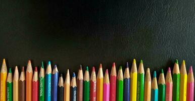 Set of colored pencils on a black background. Suitable as a background for posters, banners or templates related to education. photo