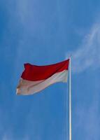 el rojo y blanco asta de bandera revolotea en contra el cielo, el indonesio bandera en el polo en contra el cielo foto
