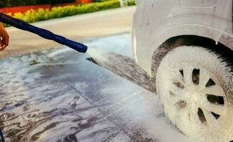 Foaming the car with the foam. Car wash. Man washing car on the self washing service. High pressure water. Pressure washer. Cleaning the car. photo