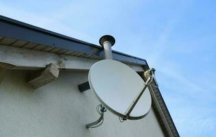 Satellite dish on the roof. Dish aerial installed to the wall. Receiving tv signals. Tv and internet connection aerial. photo