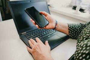 Person working on laptop. Business woman working in the office. Person holding smart phone in hand. Business concept. Modern technology in the office. photo