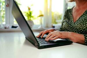 Person working on a laptop. Business woman working in the office. Conference call while working remotely. Writing on the laptop. photo