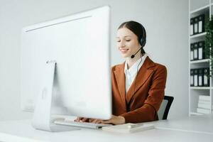 Serious call center operator in wireless headset talking with customer, woman in headphones with microphone consulting client on phone in customer support service in office center photo