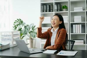 Asian business woman are delighted and happy with the work they do on their tablet, laptop and taking notes at the office. photo