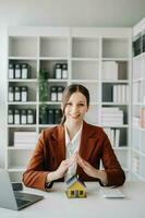 Female real estate agent is use hands to protect red roof for the concept of real estate investment about house trading, purchase at desk in office photo