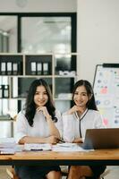 dos asiático mujer de negocios discutir inversión proyecto trabajando y planificación estrategia con tableta ordenador portátil computadora en oficina. foto