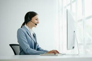 Serious call center operator in wireless headset talking with customer, woman in headphones with microphone consulting client on phone in customer support service in office center photo