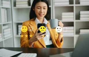 Customer service evaluation concept. Businesswoman pressing face smile emoticon show on virtual screen at tablet and smartphone photo