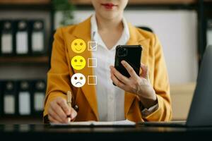 Smart Asian woman use smartphone and tablet choosing happy smile face icon. feedback rating and positive customer review experience, mental health assessment. world mental health day concept photo