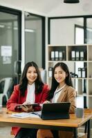 dos asiático mujer de negocios discutir inversión proyecto trabajando y planificación estrategia con tableta ordenador portátil computadora en oficina. foto