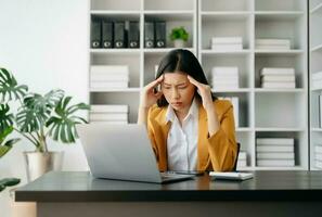 Asian business woman is stressed, bored, and overthinking from working on a tablet at the modern office. photo