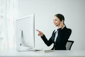 Serious call center operator in wireless headset talking with customer, woman in headphones with microphone consulting client on phone in customer support service in office center photo