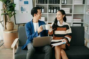 Businesswomen work and discuss their business plans. A Human employee explains and shows her colleague the results paper in modern office. photo