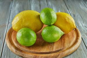 Lemons and limes on wooden stand on gray wooden background photo