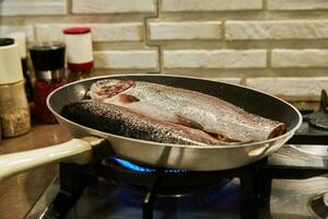 Trout is fried in pan on gas stove photo