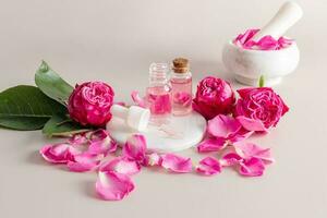 A beautiful composition of cosmetic bottles with a facial skin care product made of rose petals. pink flowers and petals. mortar with pestle. photo