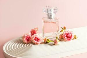 A stylish bottle of perfume stands on a white podium in the form of an arch and small pink roses. The modern image of perfume, fragrance. photo