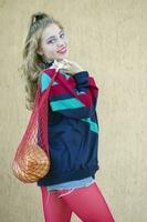 A girl in a sports trowel and red leggings keeps a string bag with a loaf. Women in the style of the nineties or eighties. photo