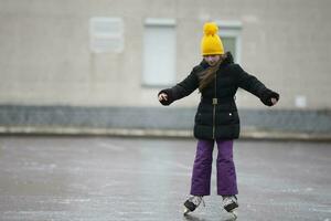 A little girl in a yellow hat is skating. photo