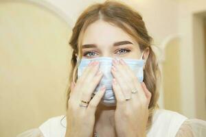 Girl in a medical mask close-up. Man's face in a blue protective mask in case of coronovirus infection. photo