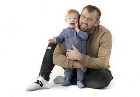 Over white background happy dad with one-year-old toddler smiling and looking at the camera. photo