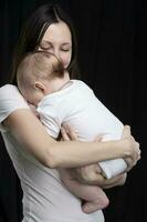 Beautiful mother hugs her baby. Motherhood.Mom and little son on a dark background. Motherhood. photo