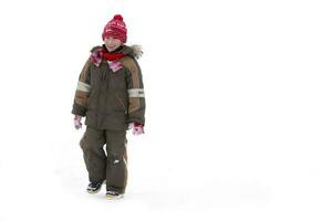 Child in winter. A boy in winter clothes walks in the snow. photo