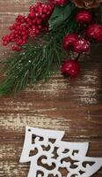 On a wooden background, a toy wooden tree and a decoration of a spruce branch and cones. Christmas background. photo