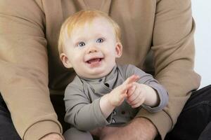 The face of a happy one year old baby in the arms of his father. photo