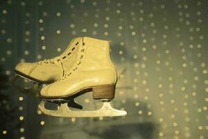 Vintage ice skates on faded green background with bokeh spots. photo