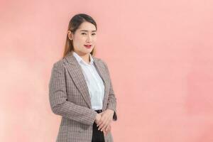 Professional Asian business woman wearing a suit standing holding hands while working at home isolated on peach color background. photo