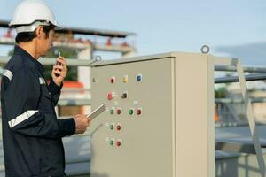 Mechanic or maintenance or electrical engineer checking main electrical control systems industrial plant. Utility fore man daily check power systems in process. Main Distribution Board, Switchboards photo