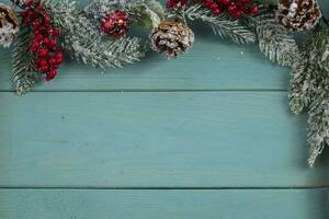 On a turquoise wood background, a decoration of a spruce branch and cones. Christmas background. photo