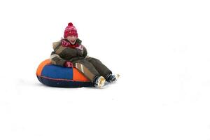 Child in winter. Cheerful boy is riding an inflatable sled. photo