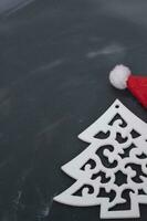 Wooden toy tree and red santa claus hat on a black background. Christmas background. photo